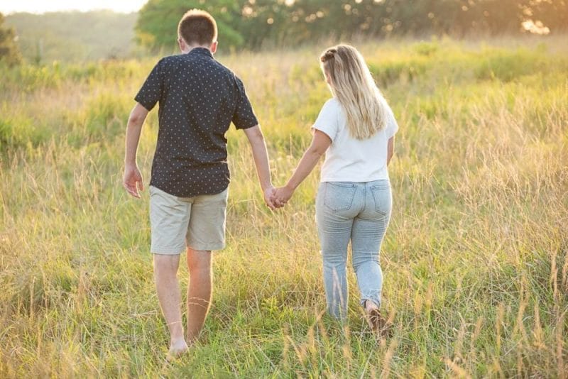couple walking through field with high grass