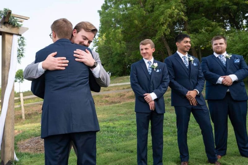 bestman and brother hugging groom at wedding ceremony