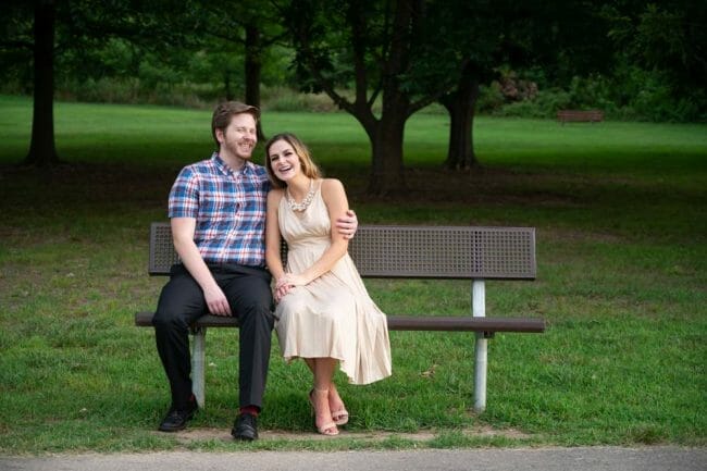 engagement photo in park sitting on bench
