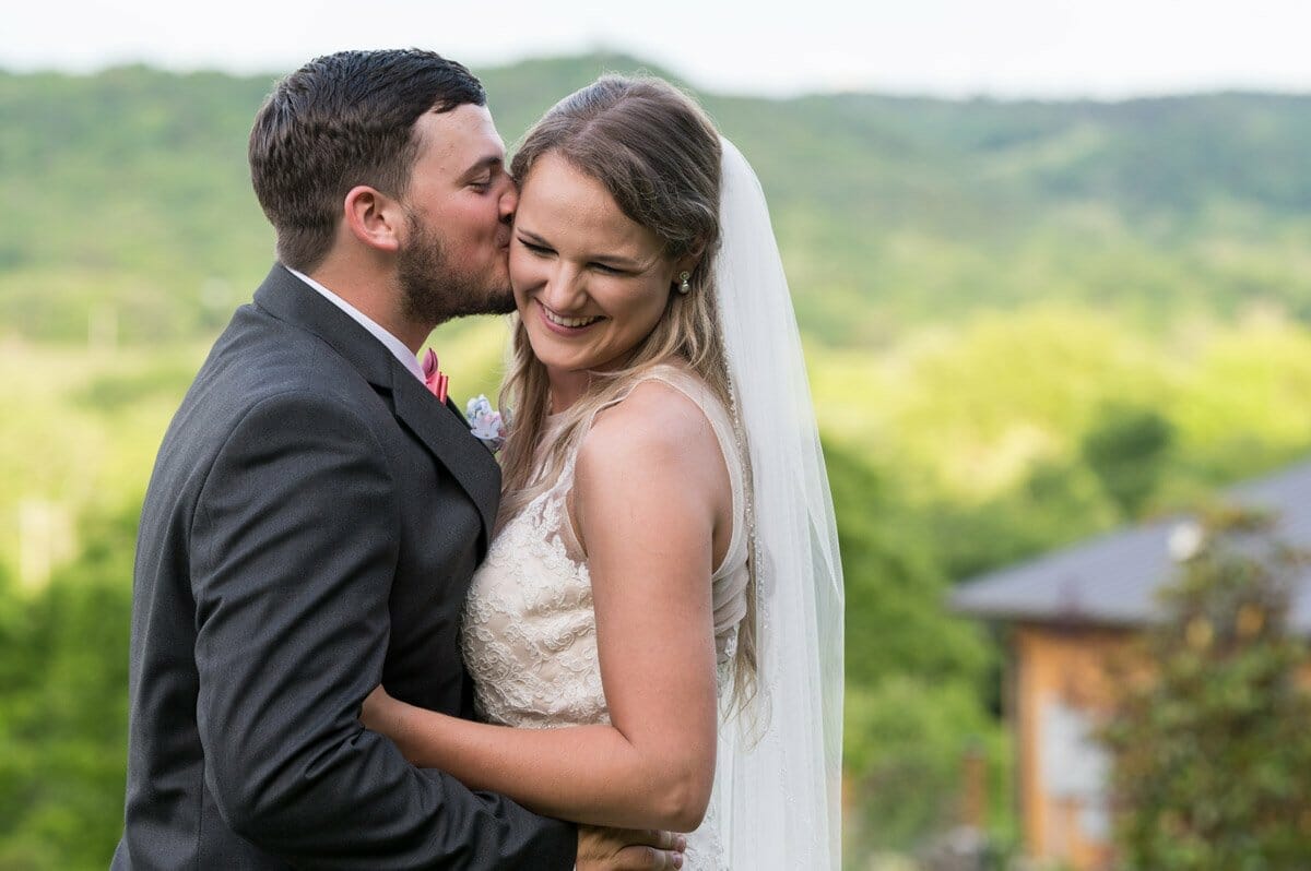bride laughing while groom kisses