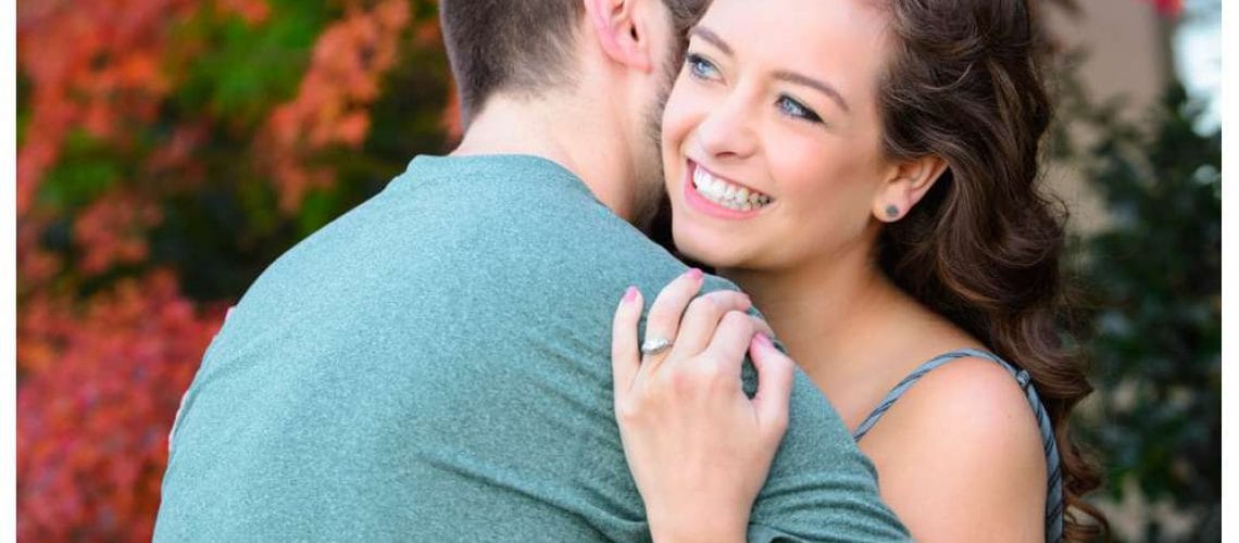 couple hugging and showing engagement ring